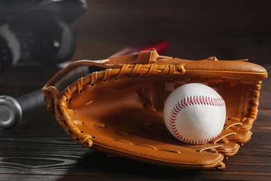 Photo of Baseball glove and ball on wooden table, closeup