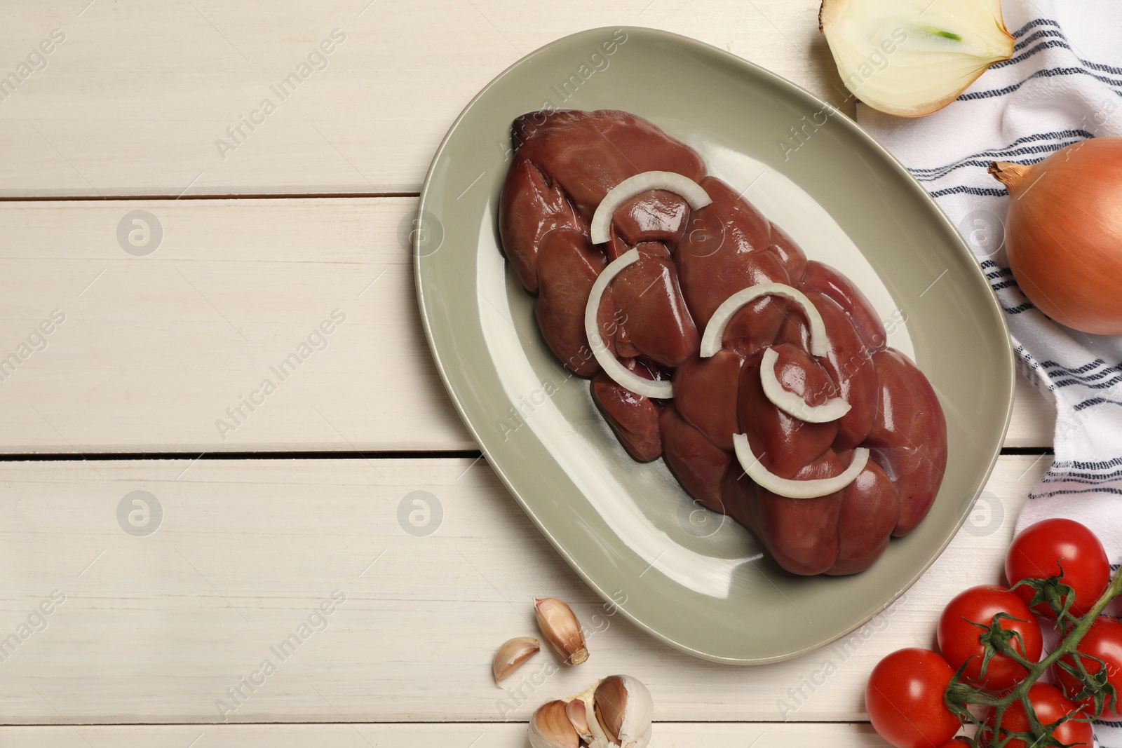 Photo of Fresh raw kidney meat and vegetables on white wooden table, flat lay. Space for text