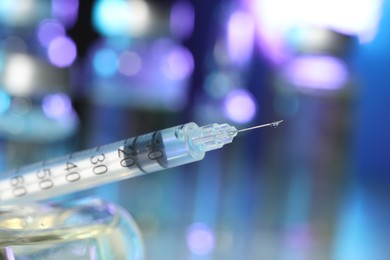 Syringe with medicine against blurred background, closeup