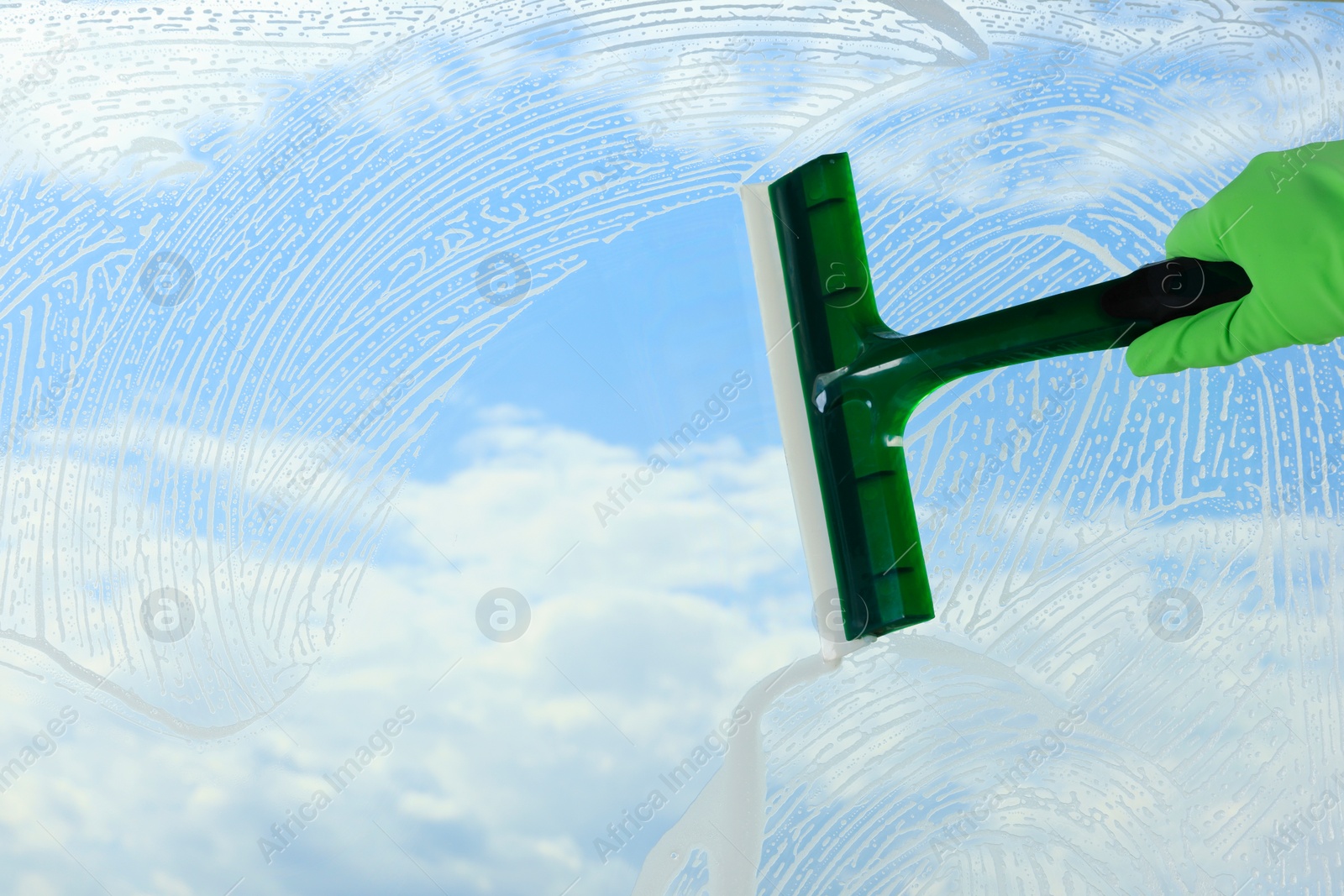 Photo of Woman cleaning glass with squeegee indoors, closeup