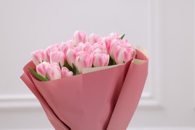 Beautiful bouquet of fresh pink tulips near white wall