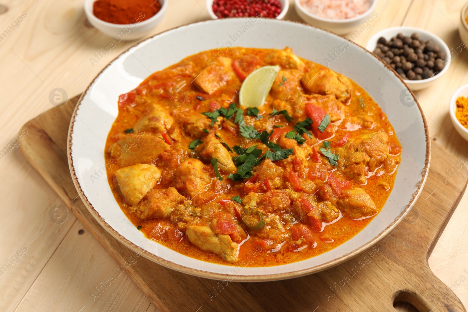 Photo of Delicious chicken curry and spices on wooden table