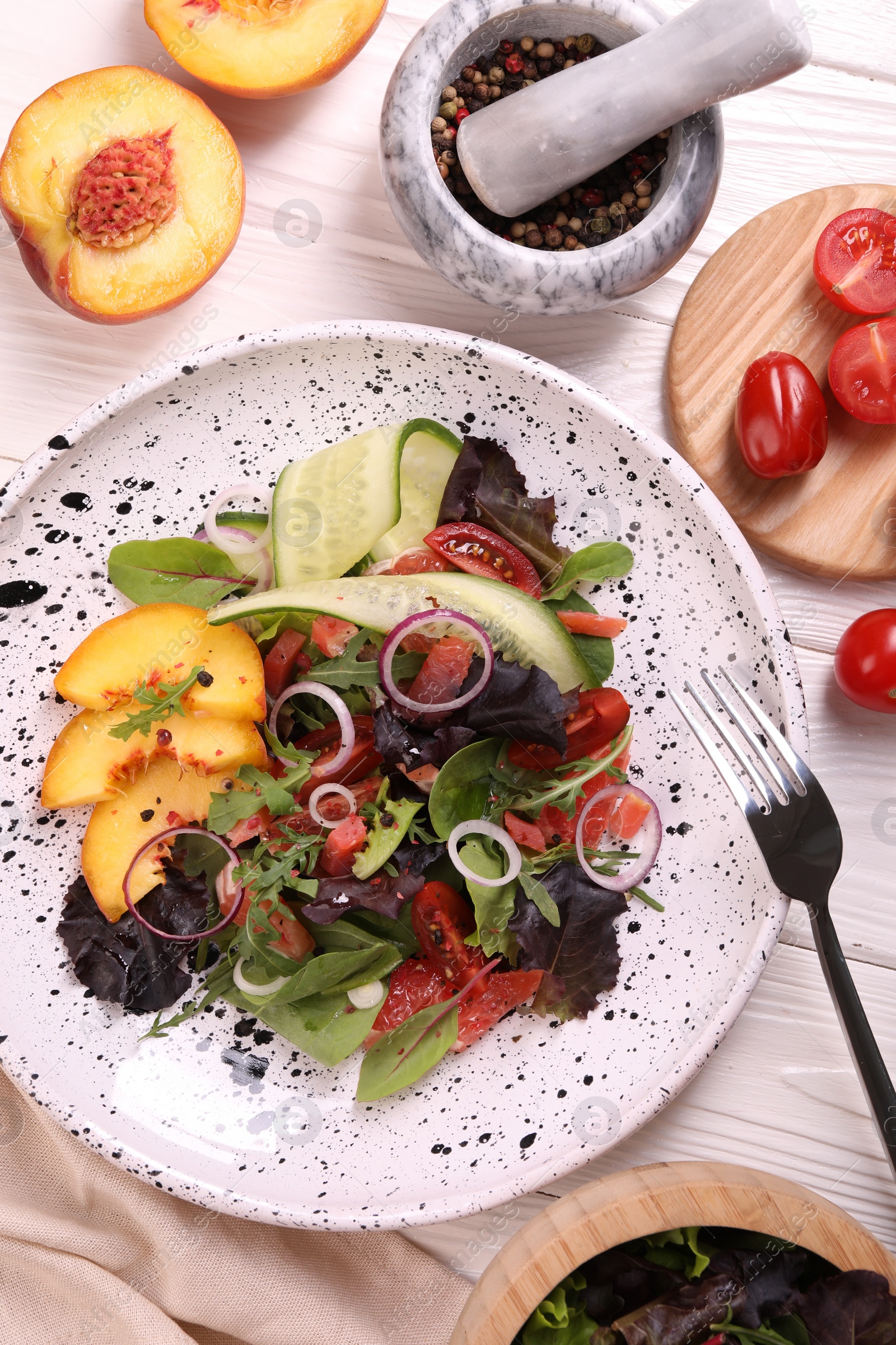 Photo of Delicious salad with vegetables and peach served on white wooden table, flat lay