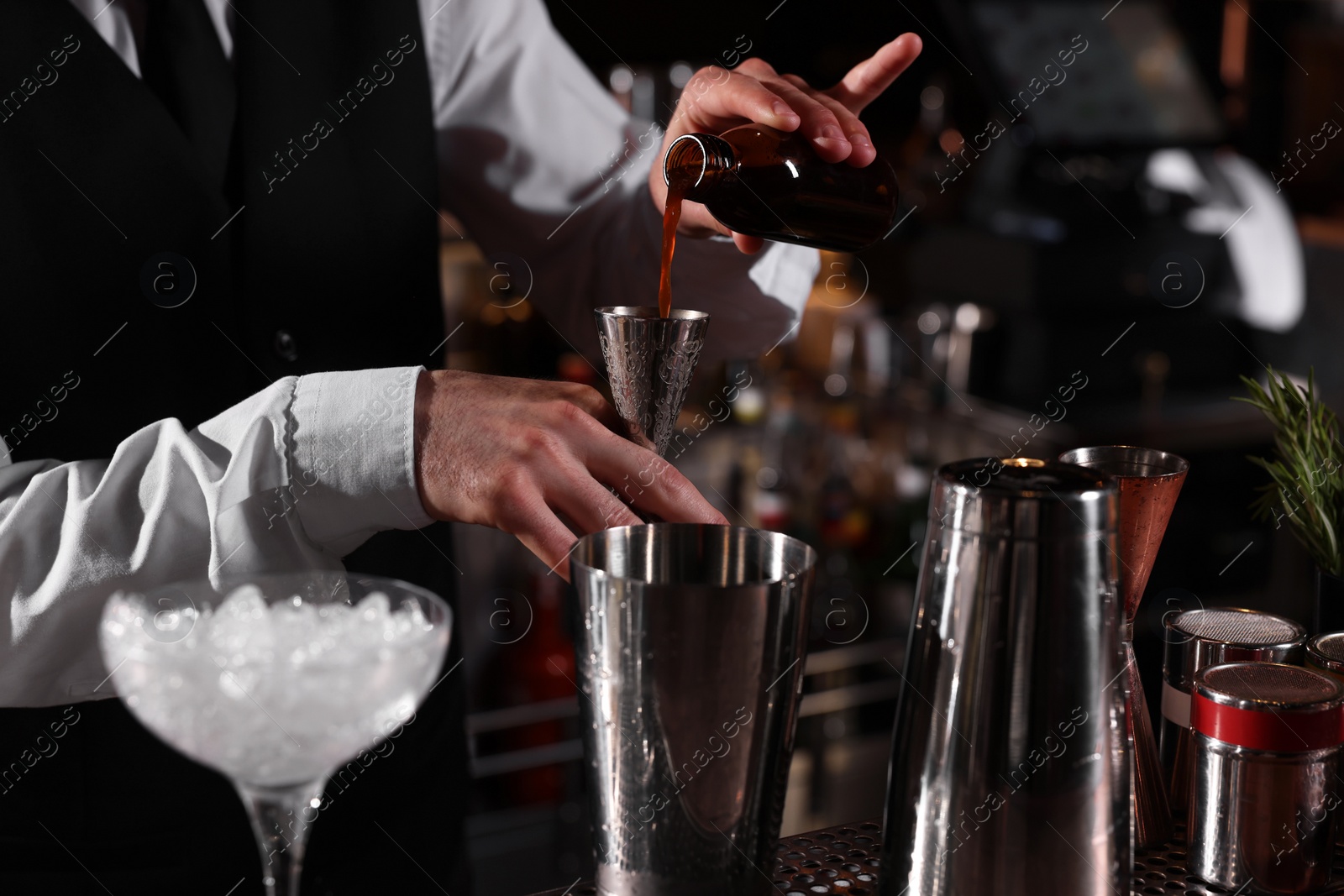 Photo of Bartender preparing fresh alcoholic cocktail in martini glass at bar counter, closeup