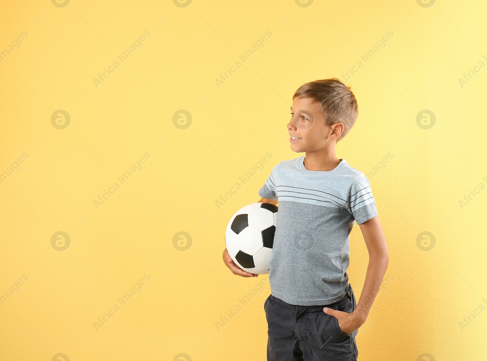 Photo of Adorable little boy with soccer ball on color background