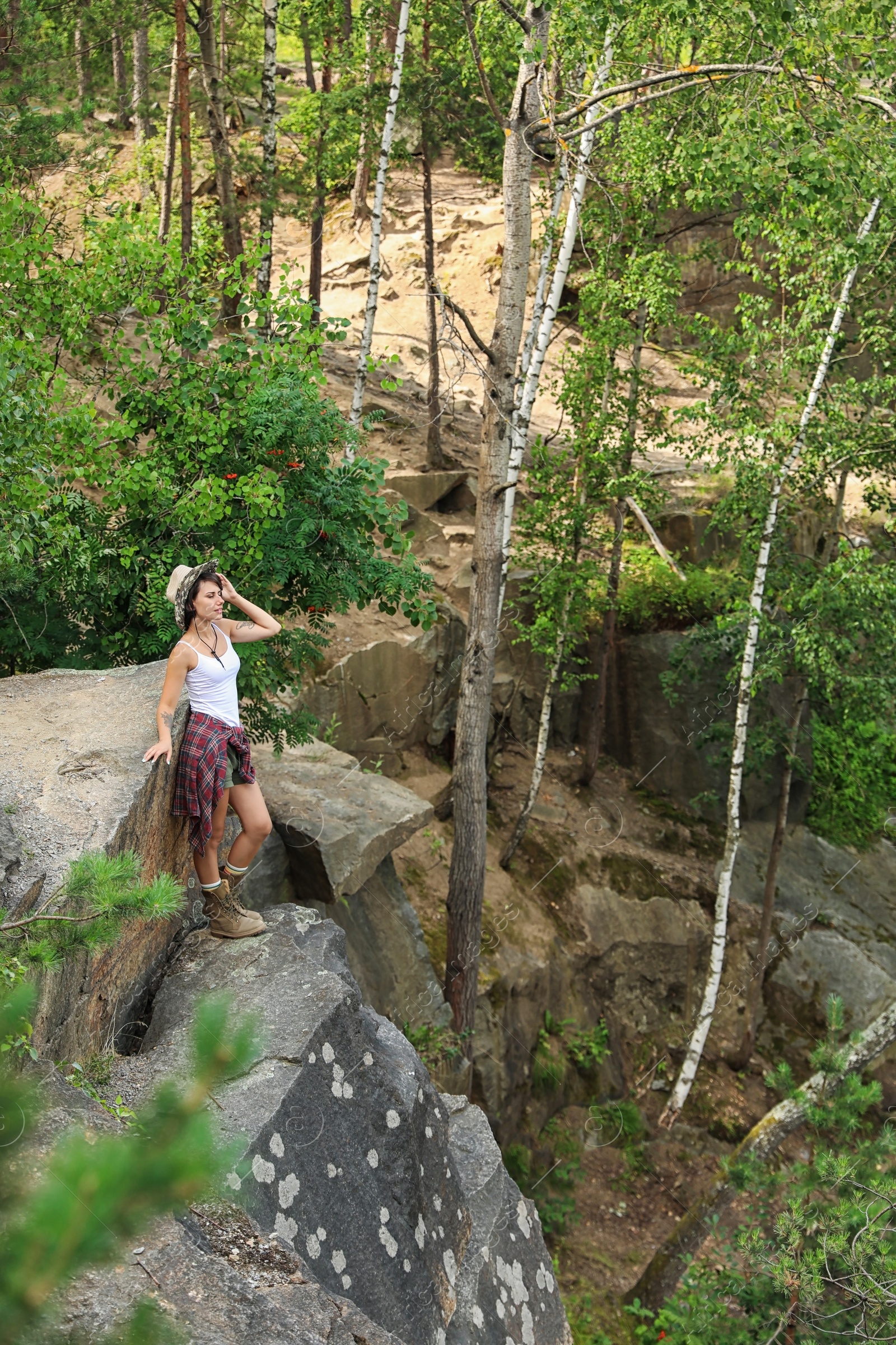 Photo of Young woman on rocky mountain in forest. Camping season