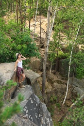 Young woman on rocky mountain in forest. Camping season