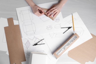 Photo of Woman creating packaging design at light wooden table, top view