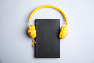 Photo of Book and modern headphones on grey background, top view