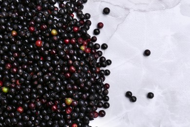 Pile of tasty elderberries (Sambucus) on white marble table, flat lay. Space for text