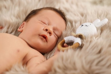 Photo of Cute newborn baby with toy sleeping on fluffy blanket, closeup
