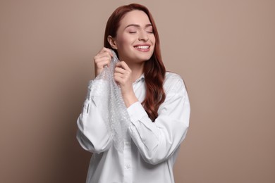 Photo of Woman popping bubble wrap on beige background. Stress relief