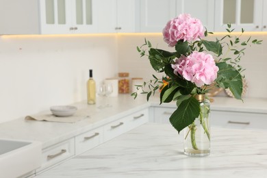 Photo of Beautiful pink hortensia flowers in vase on kitchen table. Space for text