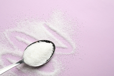 Granulated sugar and spoon on lilac background, flat lay. Space for text