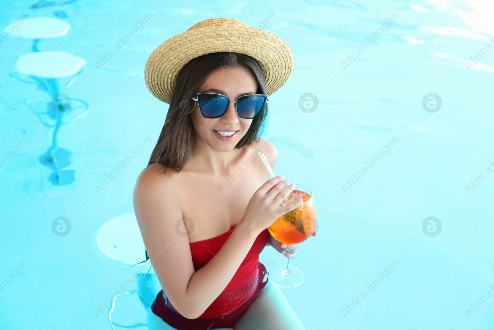 Photo of Woman with glass of refreshing drink in swimming pool