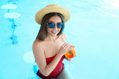 Woman with glass of refreshing drink in swimming pool