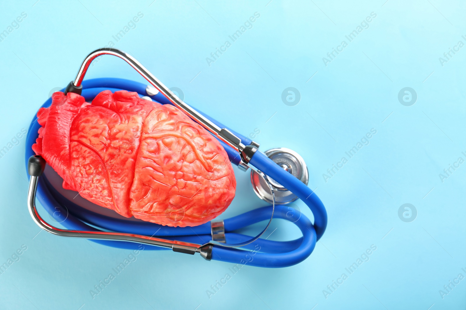 Photo of Stethoscope and model of heart on color background. Heart attack concept