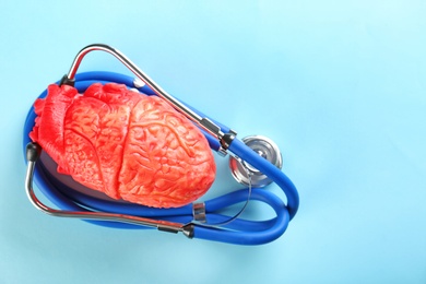 Photo of Stethoscope and model of heart on color background. Heart attack concept