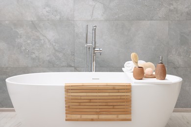 Photo of Different personal care products and accessories on bath tub in bathroom