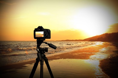 Image of Taking photo of beautiful sandy beach at sunset with camera mounted on tripod