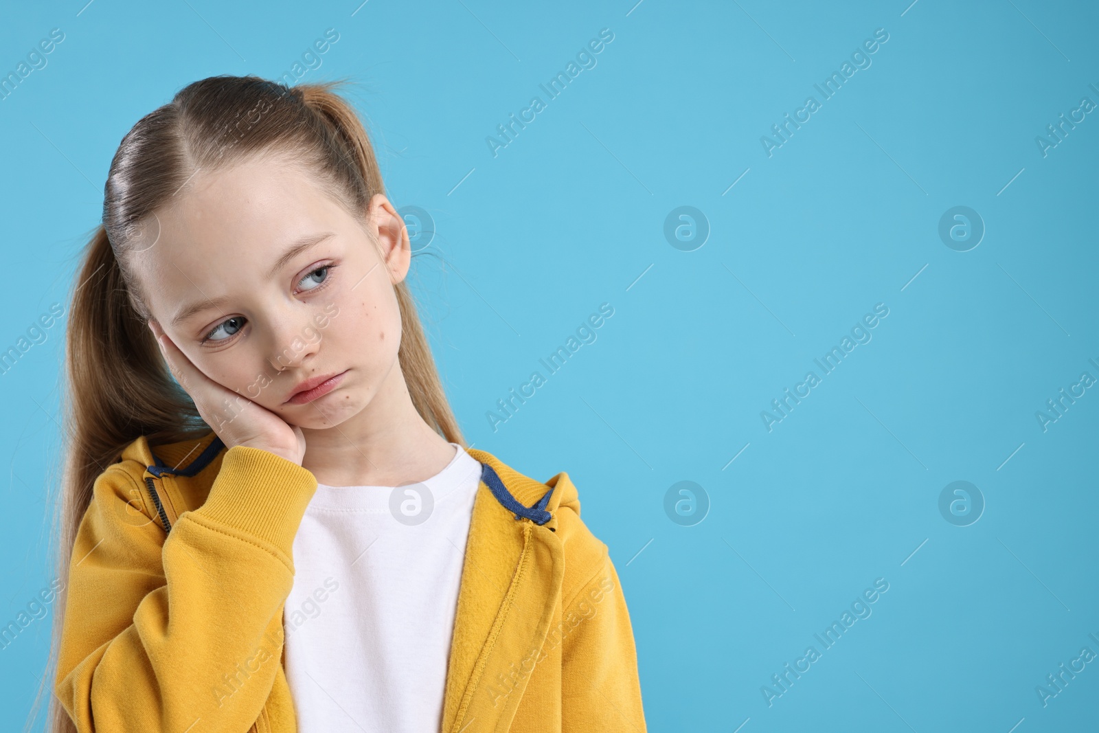 Photo of Portrait of sad girl on light blue background, space for text