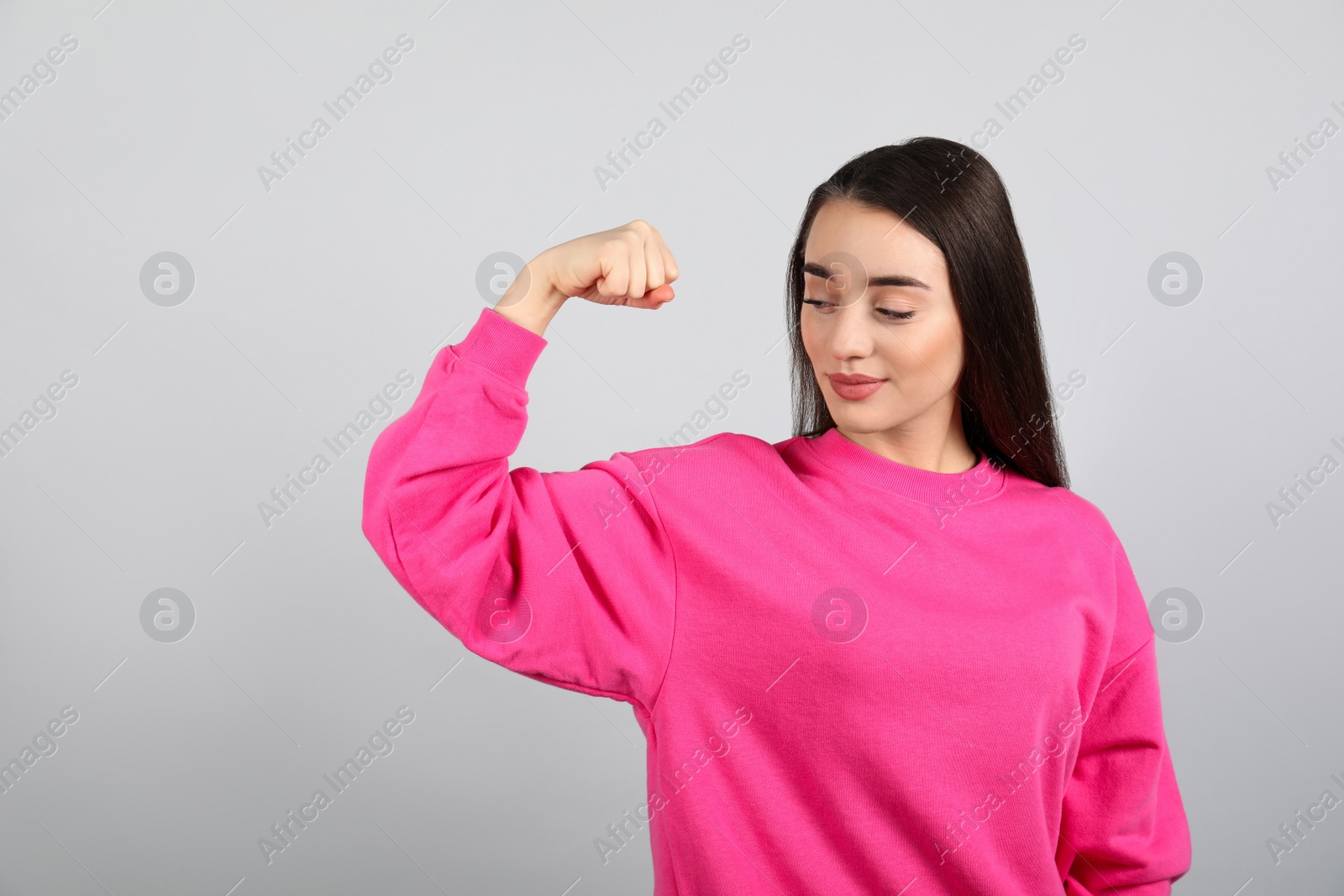 Photo of Strong woman as symbol of girl power on light grey background. 8 March concept