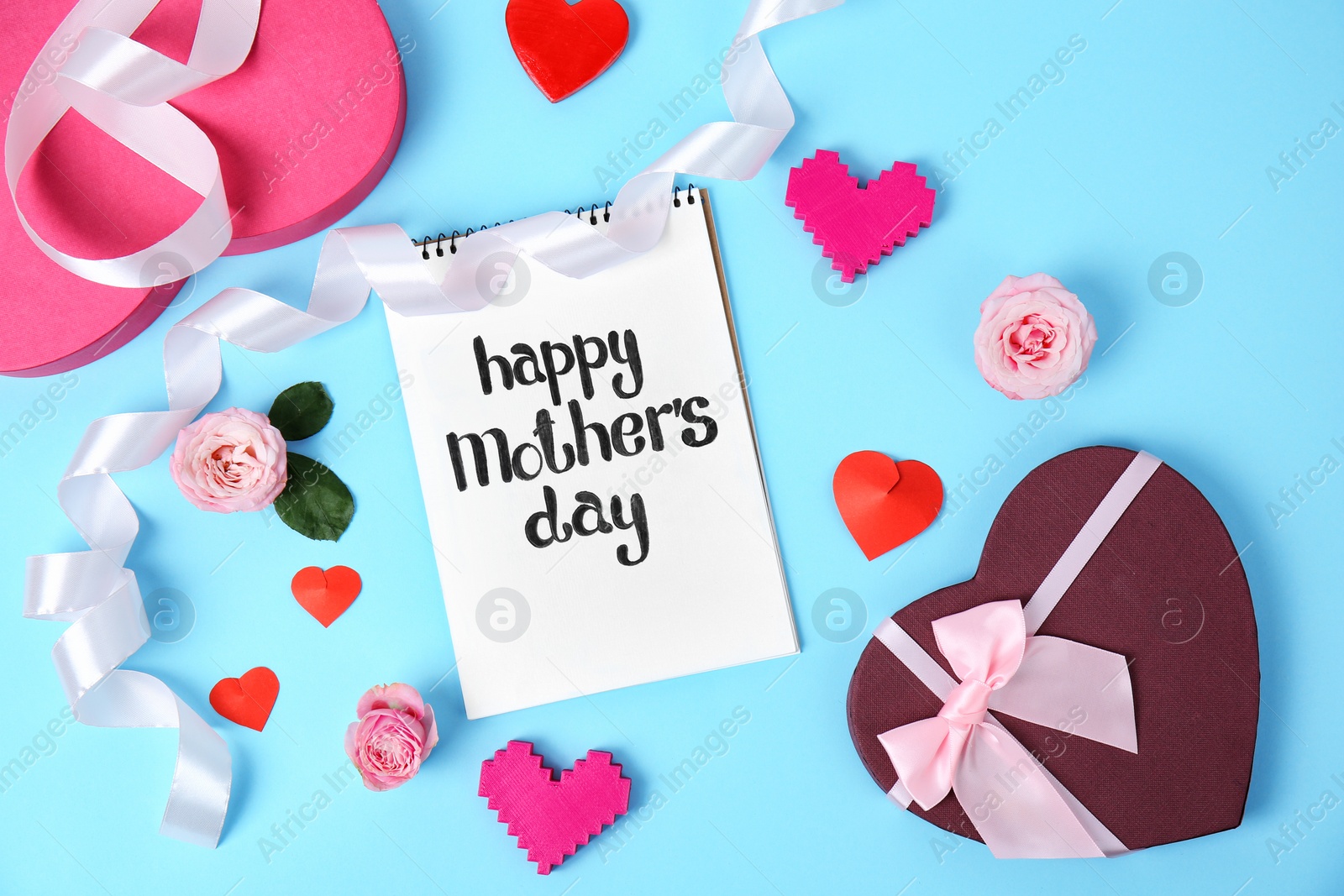 Photo of Notebook with phrase "HAPPY MOTHER'S DAY", decor and gift box on color background