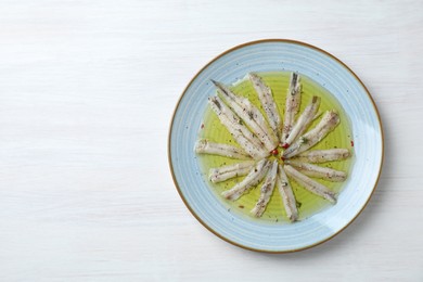 Tasty pickled anchovies with spices on white wooden table, top view. Space for text