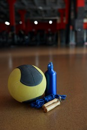 Photo of Medicine ball, bottle and skipping rope on floor in gym