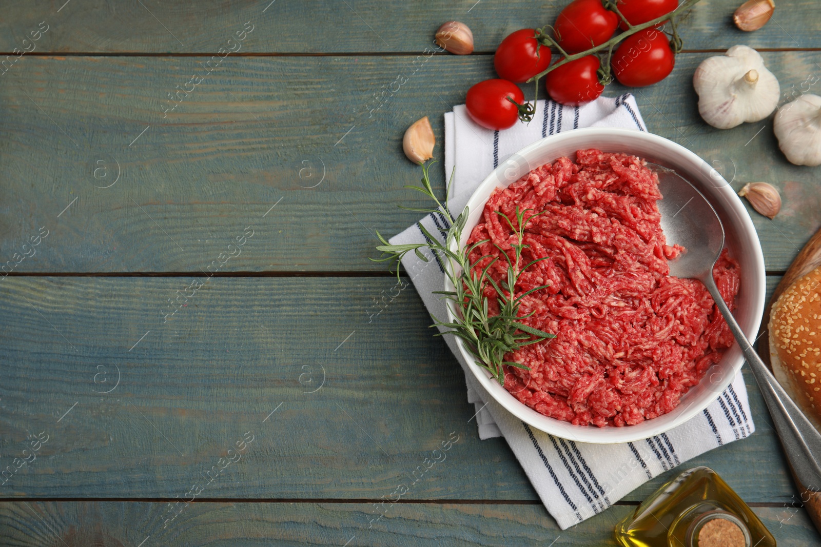 Photo of Fresh minced meat and other ingredients on light blue wooden table, flat lay. Space for text