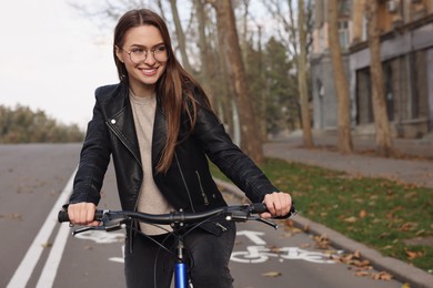 Happy beautiful woman riding bicycle on lane in city