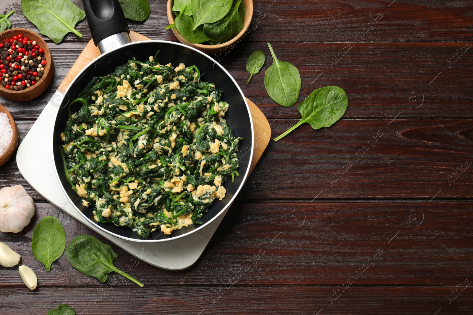 Photo of Tasty spinach dip with eggs in dish served on wooden table, flat lay. Space for text