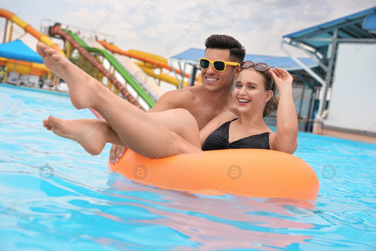 Photo of Happy couple with inflatable ring in swimming pool at water park