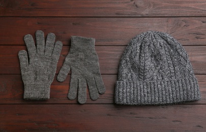 Stylish gloves and hat on wooden background, flat lay