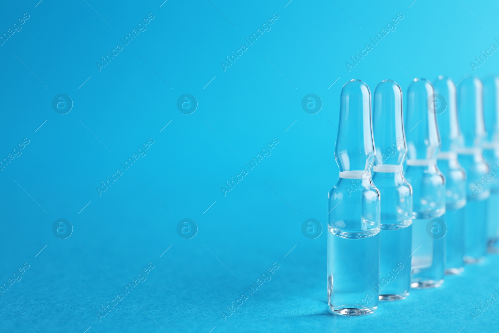 Photo of Many medical ampoules with solution on light blue background. Space for text