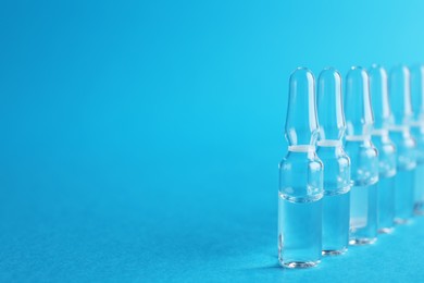 Photo of Many medical ampoules with solution on light blue background. Space for text