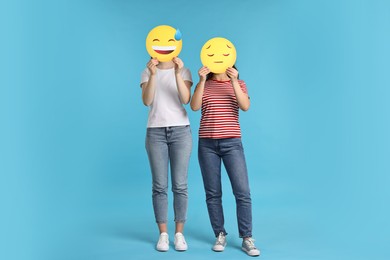 Photo of People covering faces with emoticons on light blue background