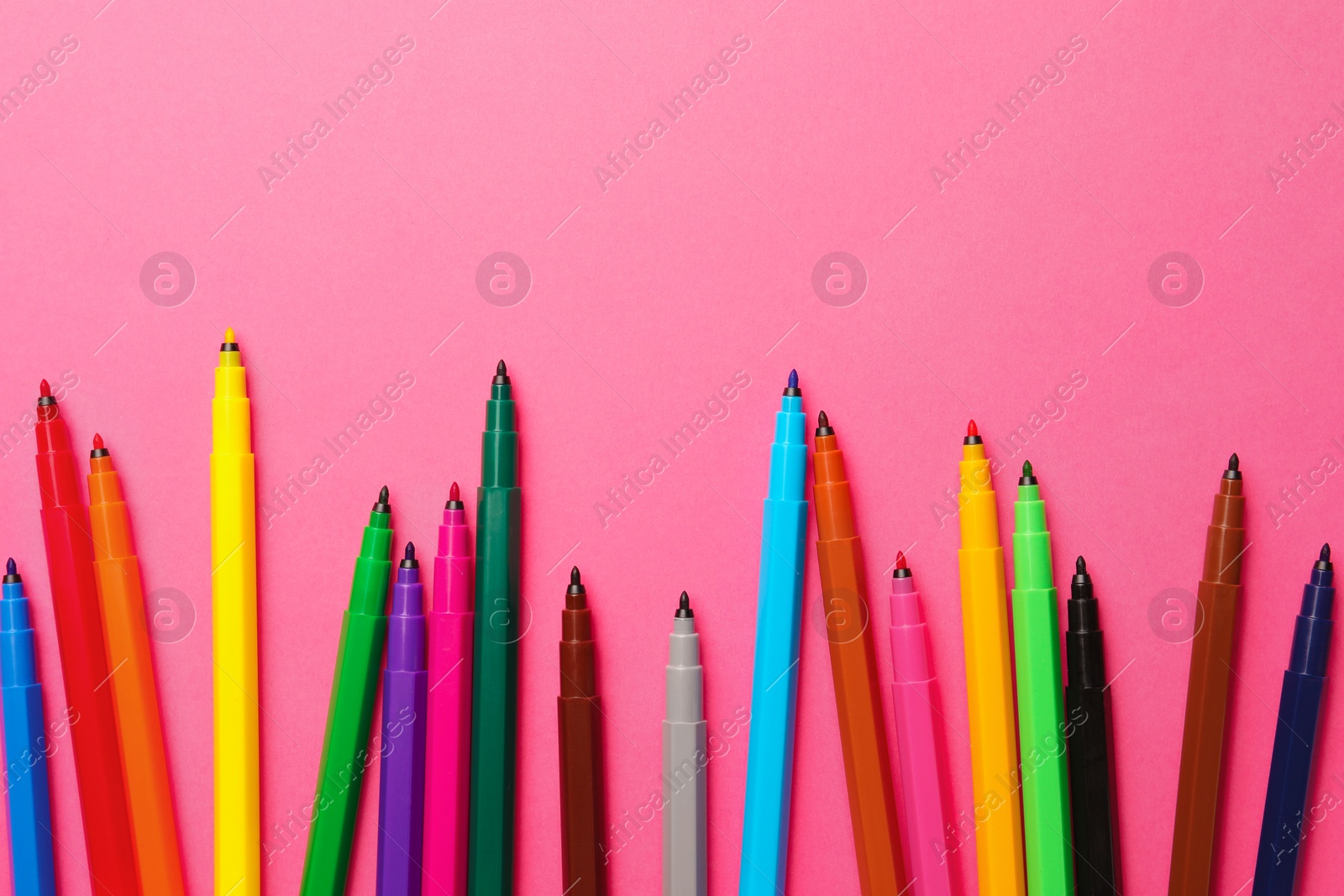 Photo of Many bright markers on pink background, flat lay. Space for text