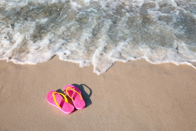 Photo of Stylish flip flops on beach. Space for text