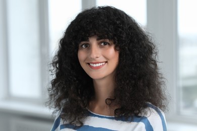 Portrait of beautiful woman in glasses indoors. Attractive lady with curly hair looking into camera