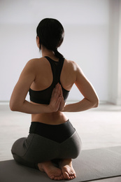 Photo of Young woman practicing seiza asana in yoga studio, back view. Vajrasana pose