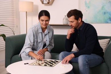 Couple playing checkers at coffee table at home
