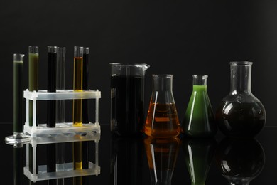 Photo of Laboratory glassware with different types of oil on black background