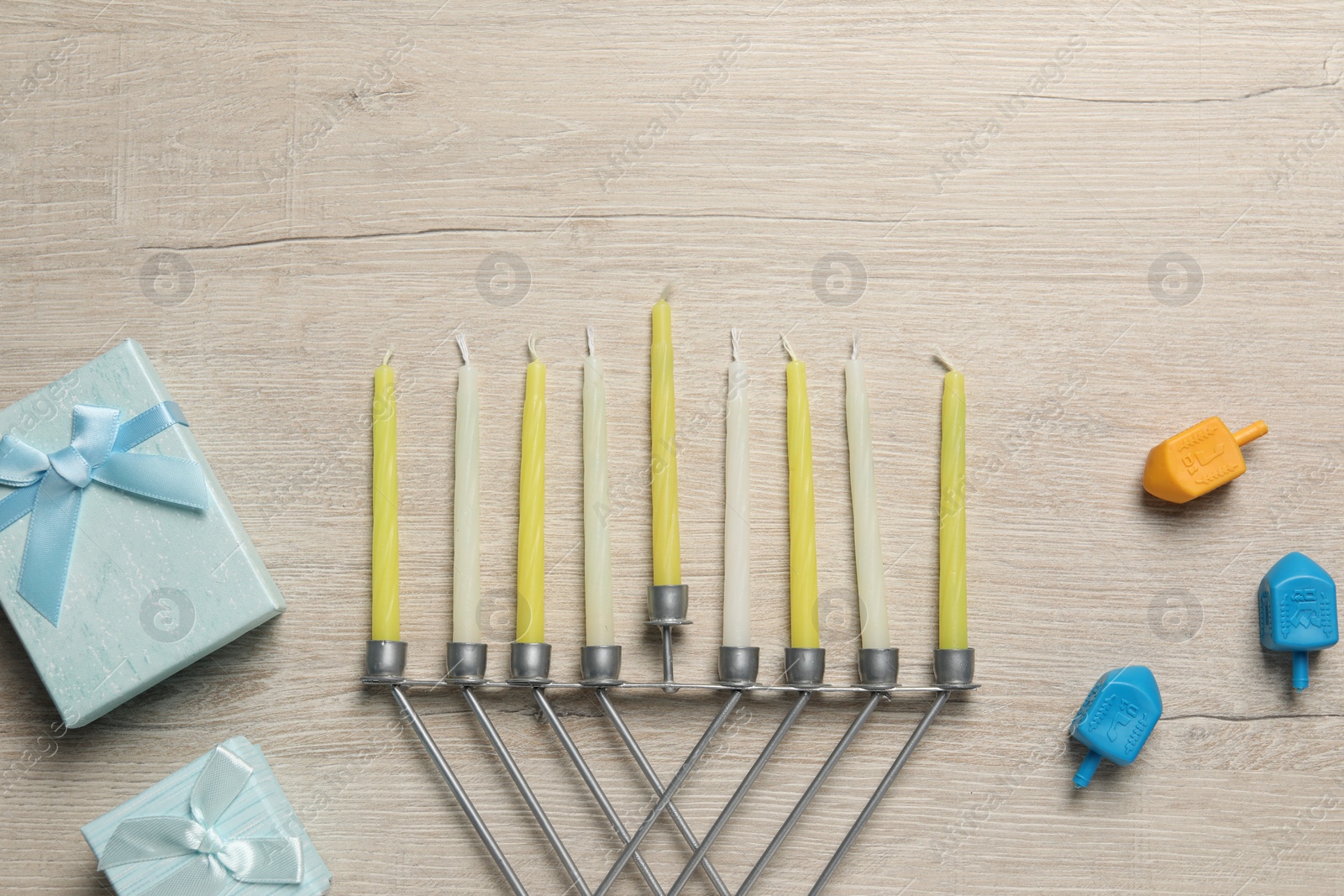 Photo of Flat lay composition with Hanukkah menorah and gift boxes on light wooden table. Space for text