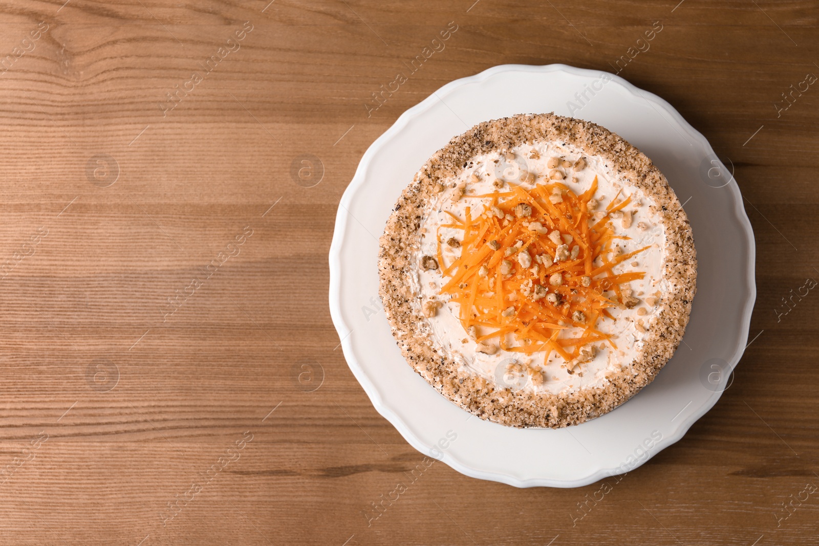 Photo of Sweet carrot cake with delicious cream on wooden table, top view. Space for text