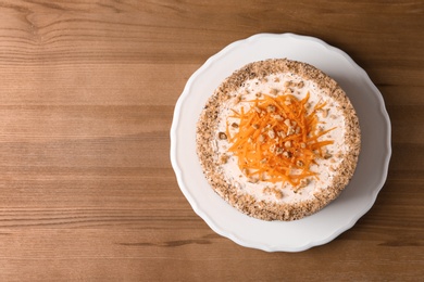 Sweet carrot cake with delicious cream on wooden table, top view. Space for text