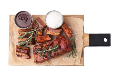 Photo of Tasty roasted pork ribs, rosemary and sauce isolated on white, top view