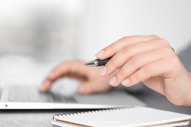 Photo of Woman with pen working on laptop, closeup. Electronic document management