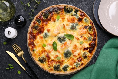 Photo of Delicious homemade salmon quiche with broccoli served on black table, flat lay