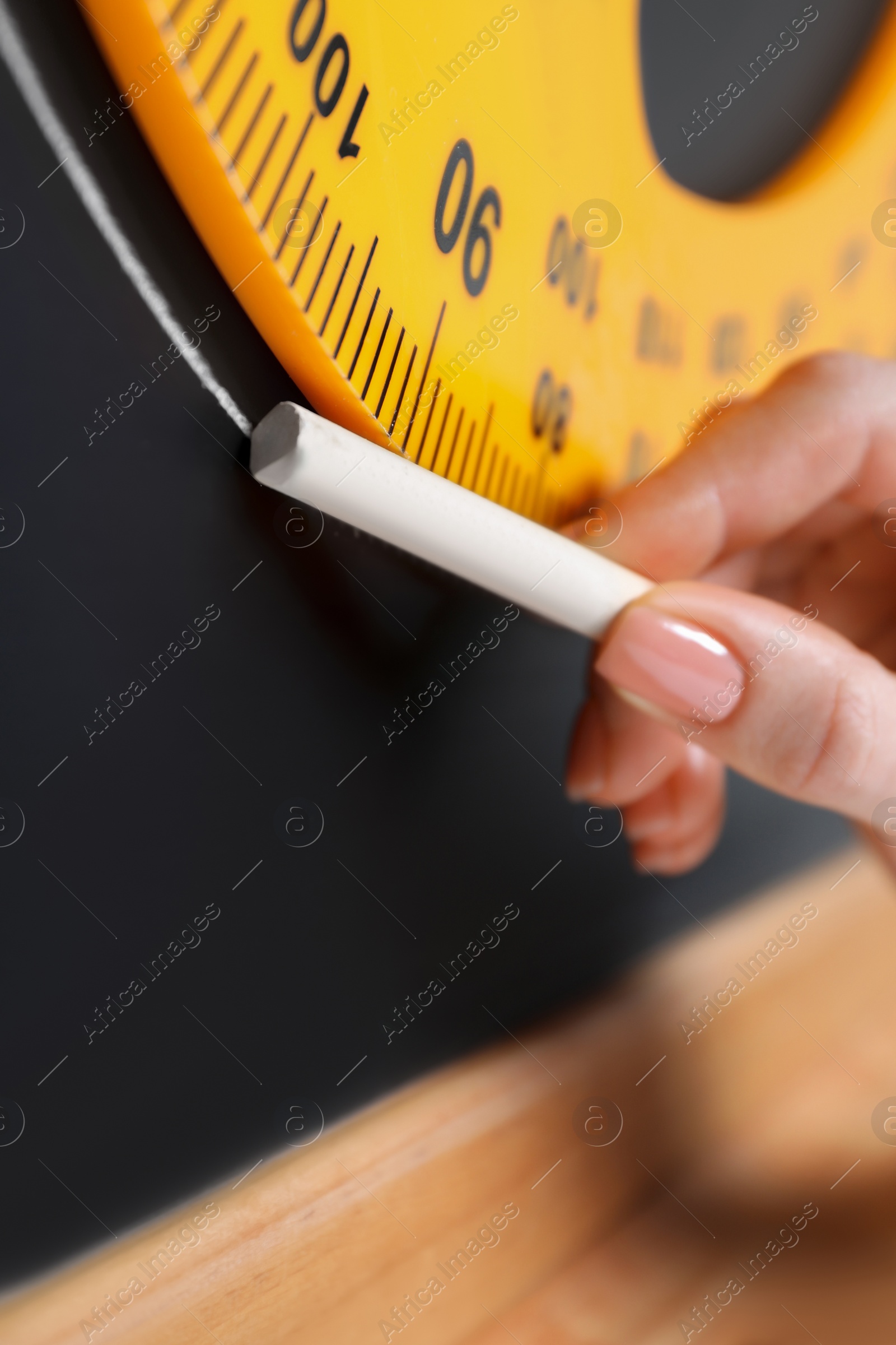 Photo of Woman drawing with chalk and protractor on blackboard, closeup